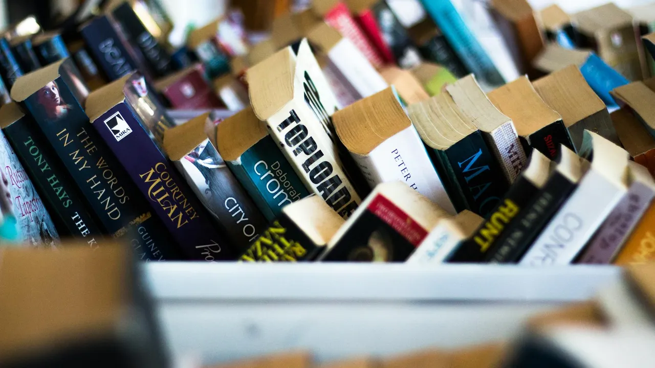 Close-up of overlapping book spines on a shelf with varied colors and fonts.