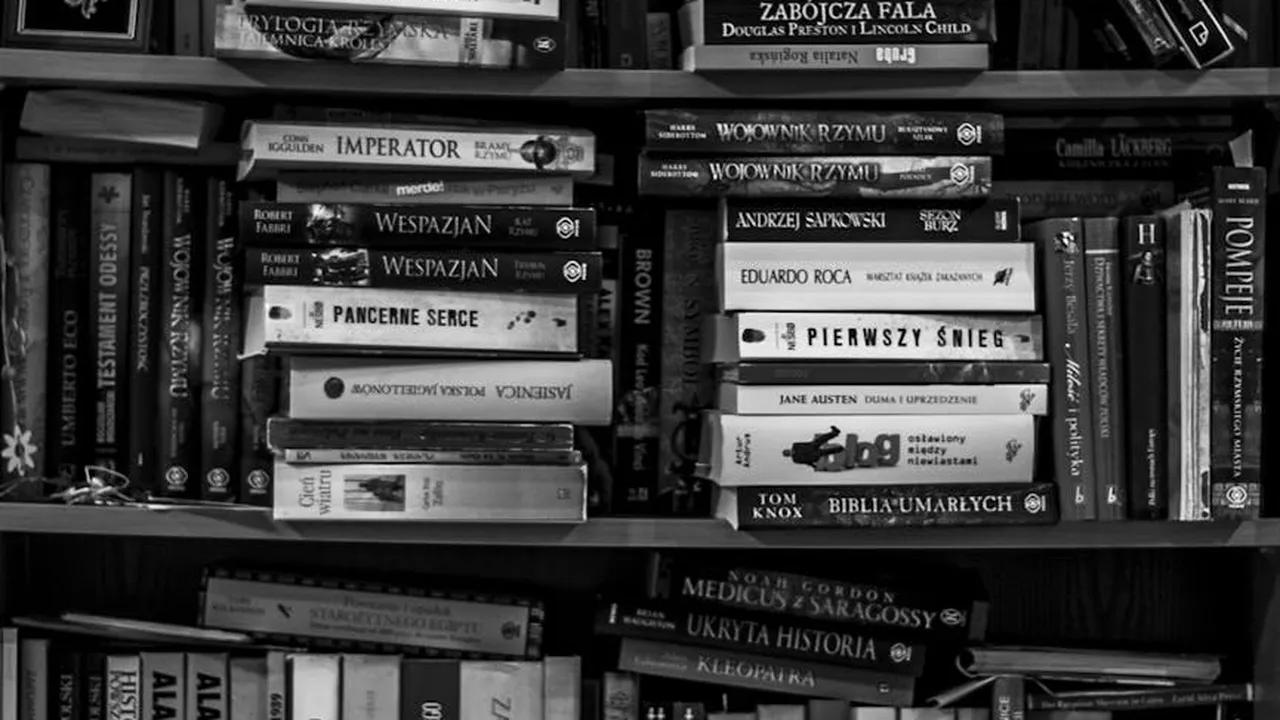 Grayscale photo of a bookshelf filled with romance novels, suggesting intense relationships and trauma-centered love stories