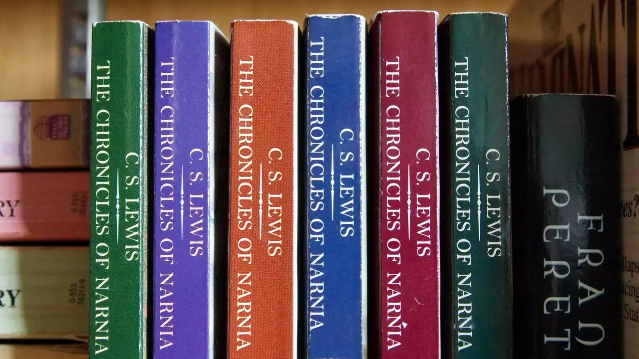 Spines of The Chronicles of Narnia novels by C.S. Lewis in different colors on a shelf