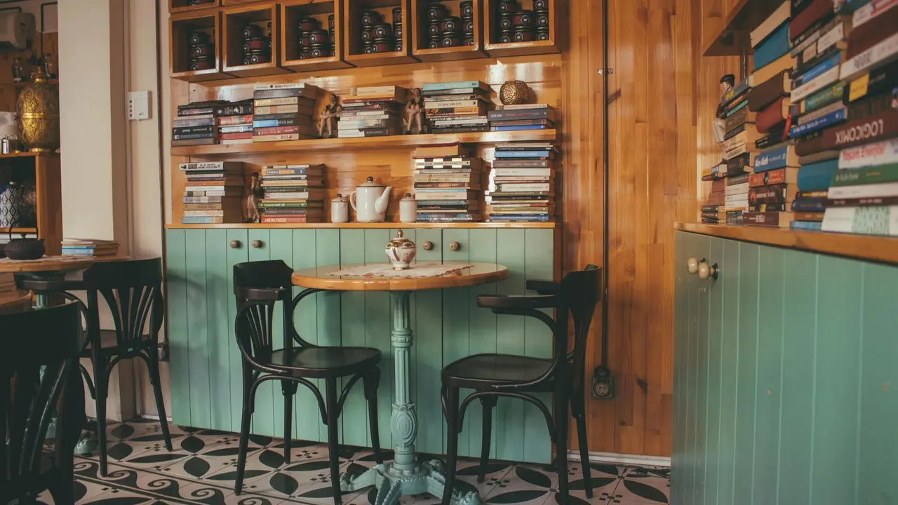 Interior of a cozy bookstore café with wooden shelves filled with books, a round wooden table, and black chairs.