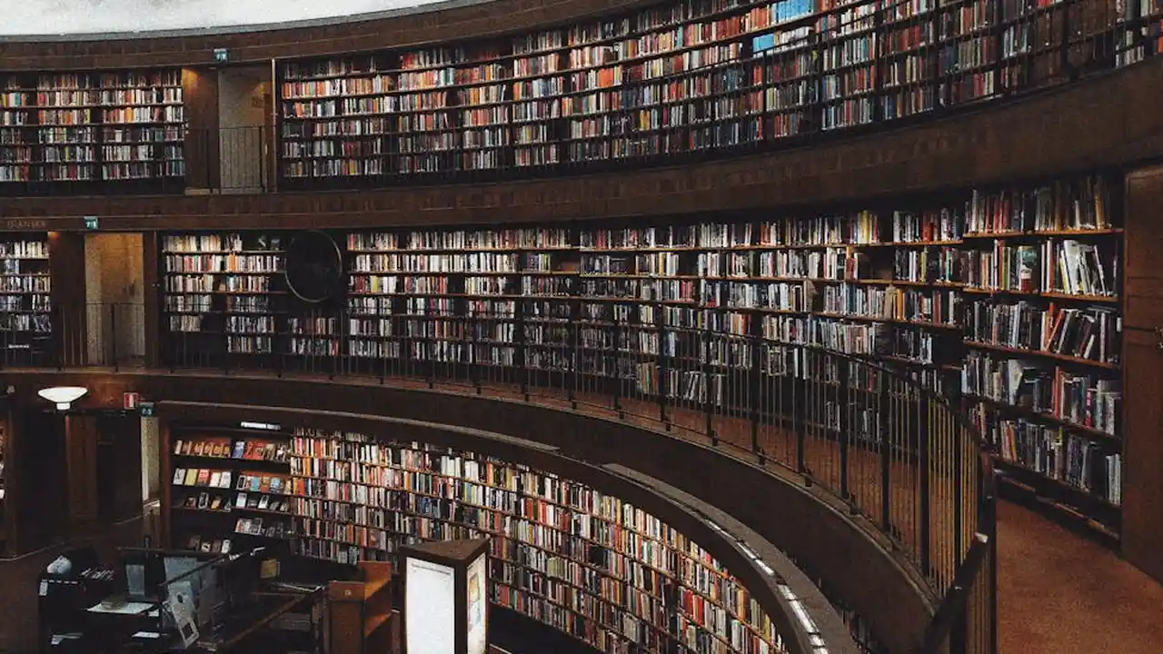 Curved multi-tiered library shelves densely packed with books in a quiet reading room.