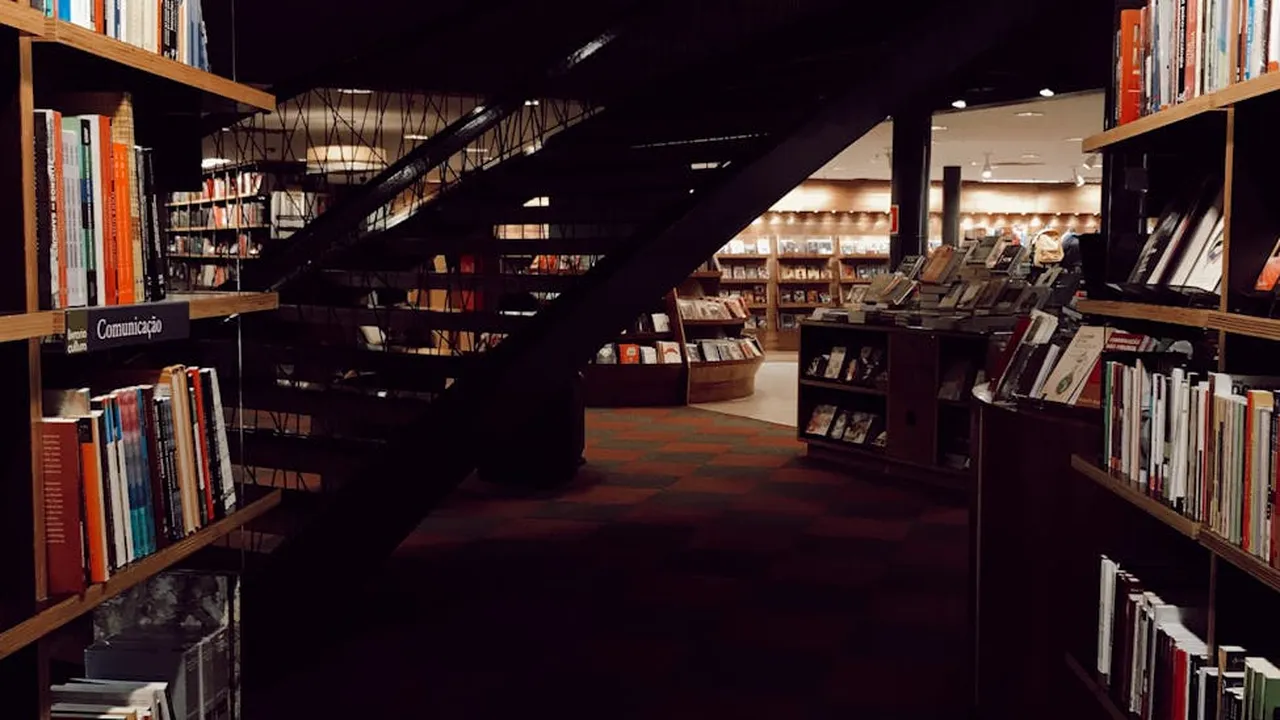 Dimly lit library with tall shelves of books and a staircase, creating a contemplative space for exploring the mind.