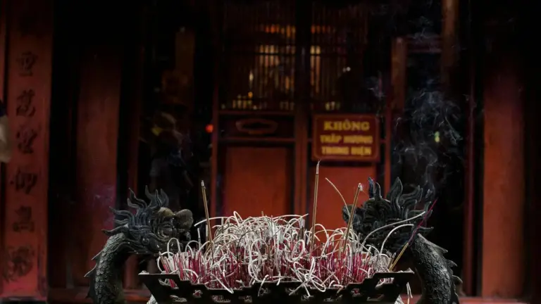Two dragon sculptures flank a ceremonial altar in a dim temple, with red offerings in the center.