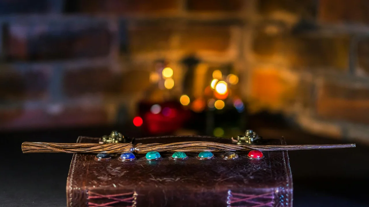 A slender twig laid across a dark surface with colorful beads threaded along it, set against a warm, blurred brick backdrop.