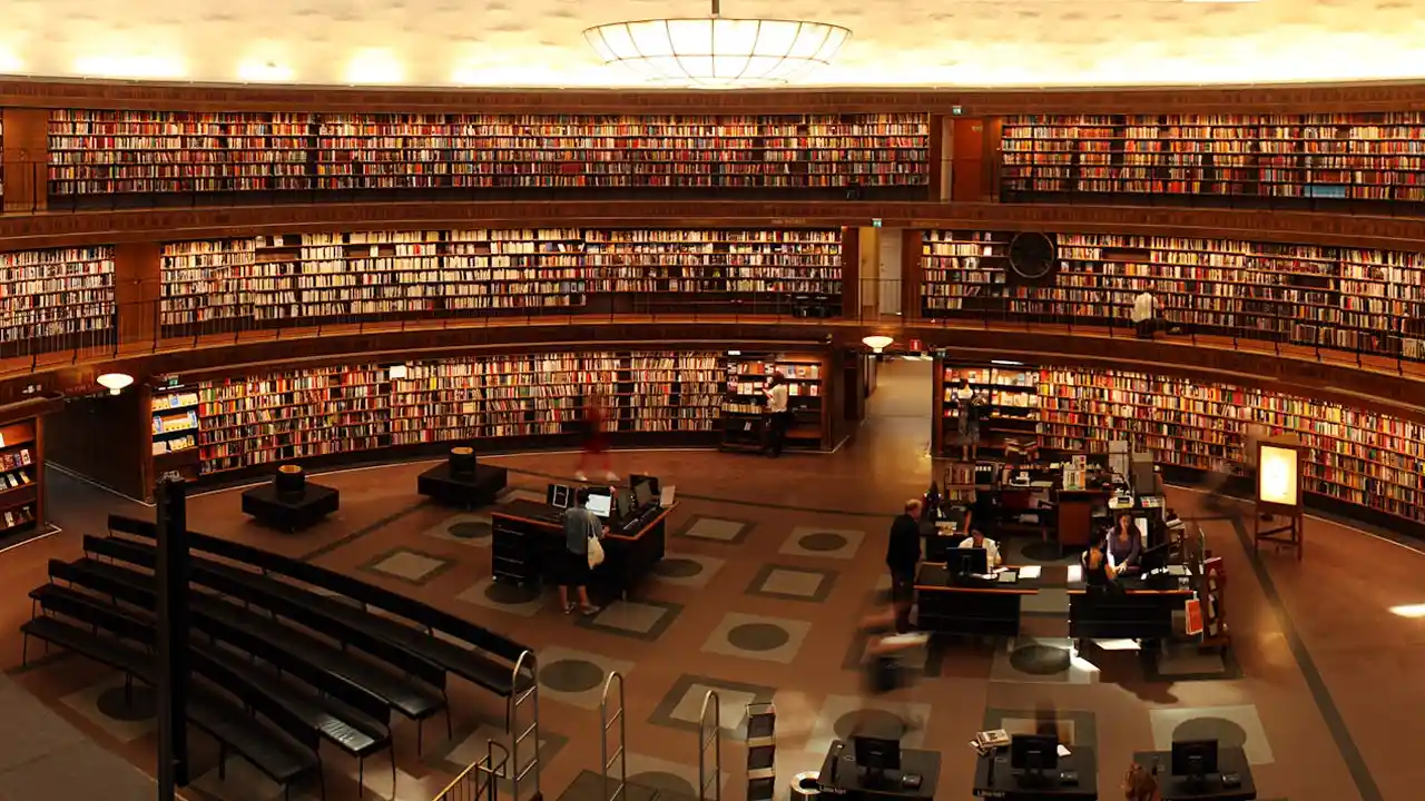 Interior of a large library with curved shelves filled with books and readers at tables.
