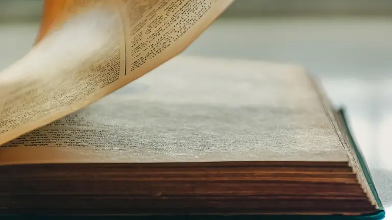 Open hardcover book with a curling page, suggesting nostalgia and immersive reading.