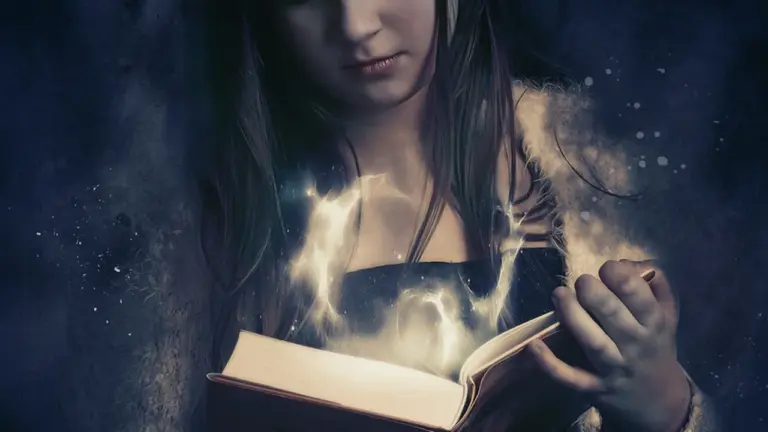 A young woman reads a glowing, magically lit book as light swirls from its pages.
