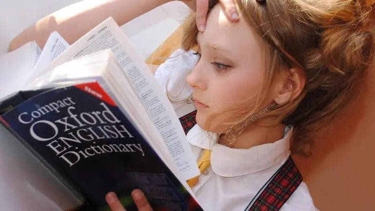 Woman reading a Compact Oxford English Dictionary with pages open