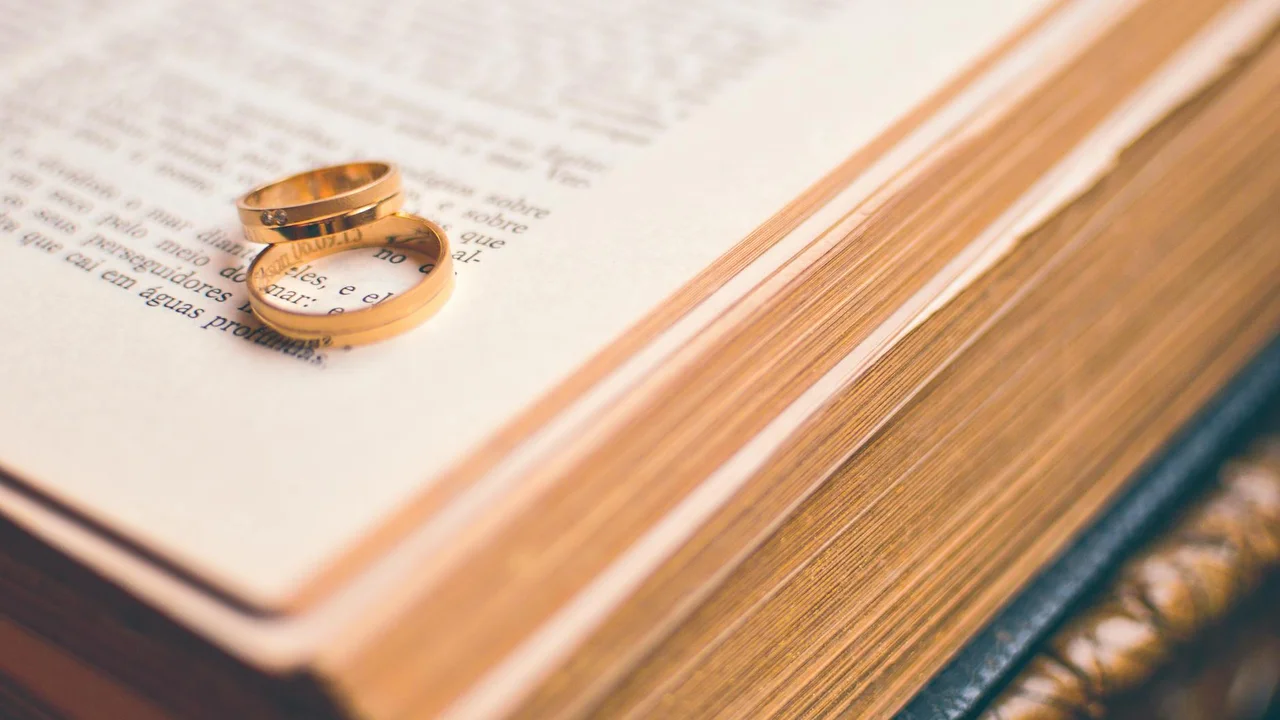 A pair of wedding rings rests on the pages of an open book, symbolizing practical marriage advice.