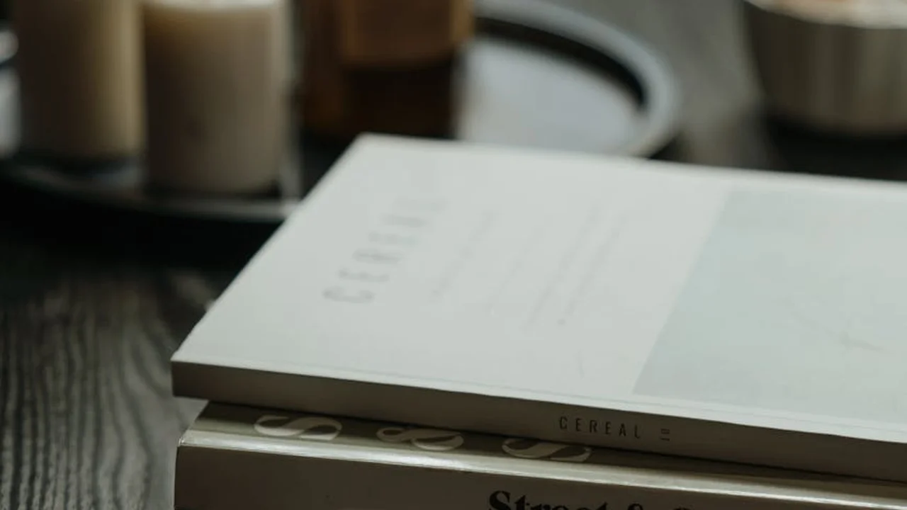 Close-up of two books stacked on a dark wooden table with out-of-focus candles in the background