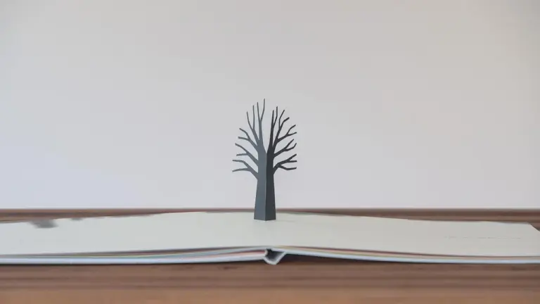 Open children's book with a silhouette of a bare tree rising from its pages, symbolizing growth and self-belief.