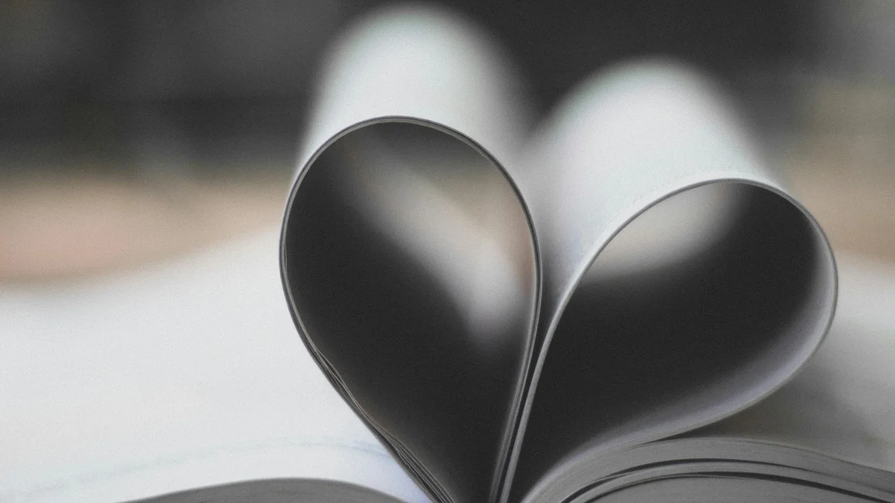 Close-up of a folded paper heart in grayscale with a soft, blurred background