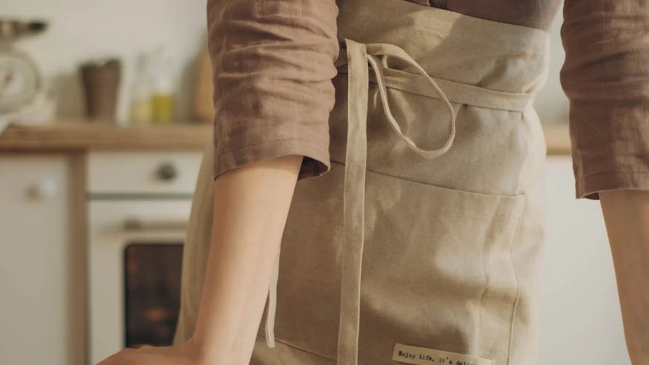Person wearing a beige apron standing in a cozy kitchen