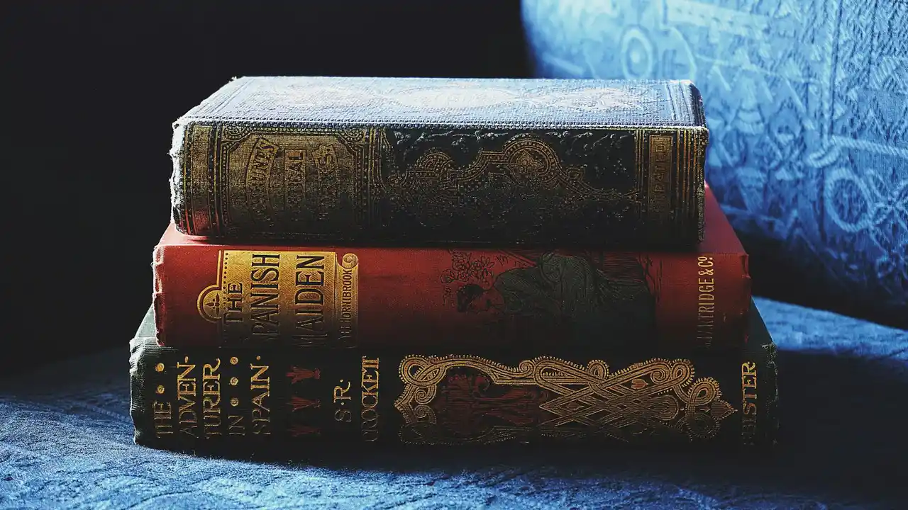 Stack of vintage hardcover horror and suspense novels with ornate spines resting on a blue couch